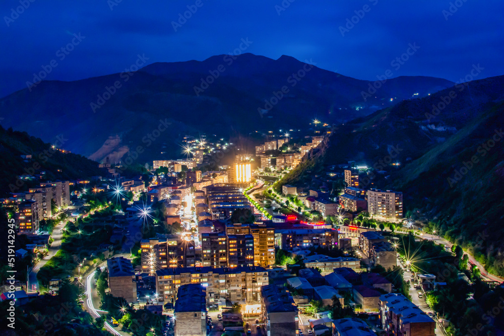 Night city from a bird's eye view. The light of houses and cars. A beautiful city with rivers, bridges and beautiful buildings. City among the mountains, Kapan, Armenia