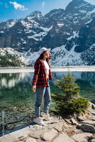 A woman is standing on the shore of a lake. Morskie Oko, Tatras mountains.