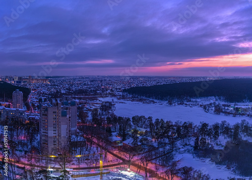 Sunset over the outskirts of the city of Kyiv and snow-covered forest in winter. Kyiv, Ukraine