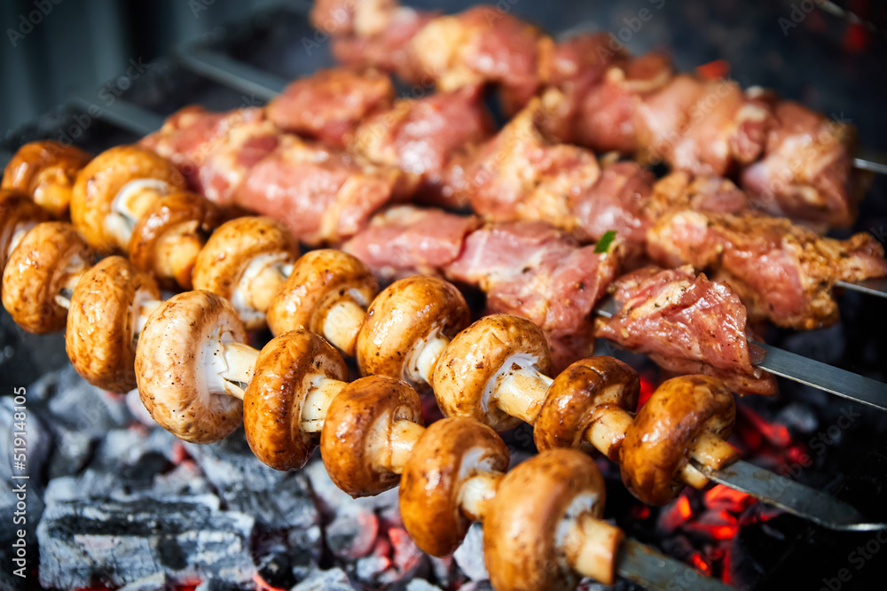Champignon mushrooms and pieces of pork are grilled on skewers on the grill