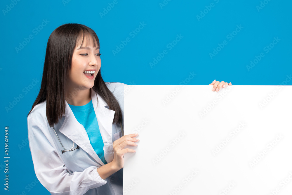 Smiling doctor holding blank banner or card with stethoscope on blue background Smiling doctor holding blank banner or card with stethoscope on blue background