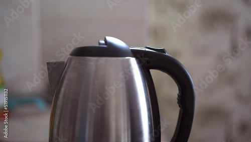 Button for turning on the electric kettle for boiling water. An electric kettle boils water. Person turns on the electric kettle. photo