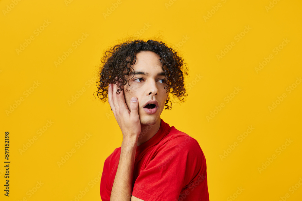 Shocked confused funny Caucasian young man in red t-shirt touches cheeks posing isolated on over yellow studio background. The best offer with free place for advertising. Emotions for everyday concept Shocked confused funny Caucasian young man in red t-shirt touches cheeks posing isolated on over yellow studio background. The best offer with free place for advertising. Emotions for everyday concept