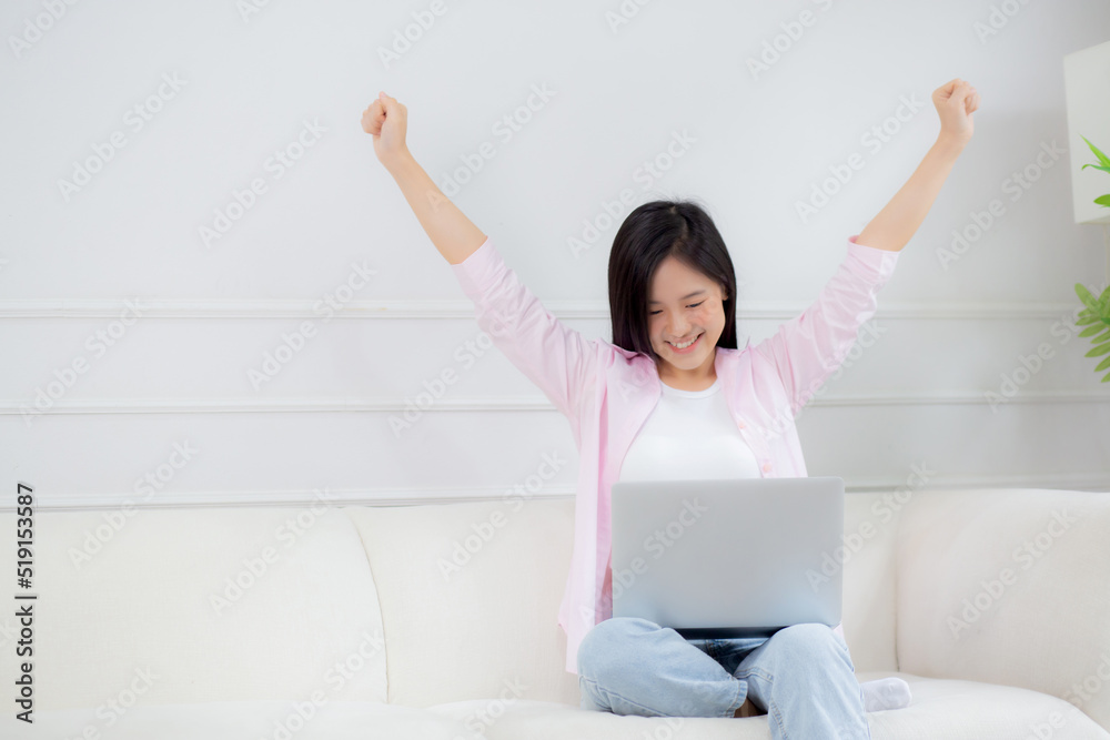 Happiness young asian woman sitting on sofa and working on laptop computer while successful and excitement at home, freelance female using notebook and achievement, business and lifestyles concept. Happiness young asian woman sitting on sofa and working on laptop computer while successful and excitement at home, freelance female using notebook and achievement, business and lifestyles concept.