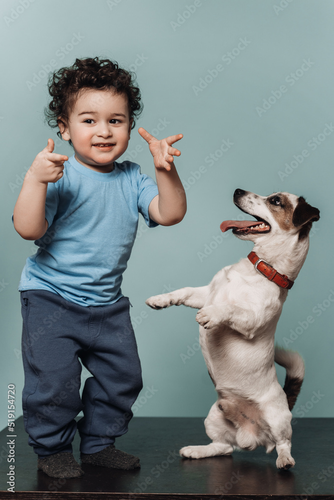 Little boy with curly hair in casual dancing on the table with a