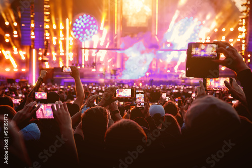 People raised their mobile phones to record live concert. People smartphones on the music show festival.