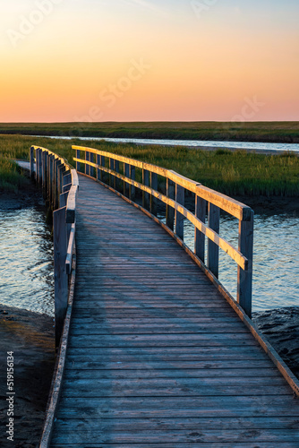 View of a wooden bridge in Langwarder Groden/Germany on the North Sea at sunset