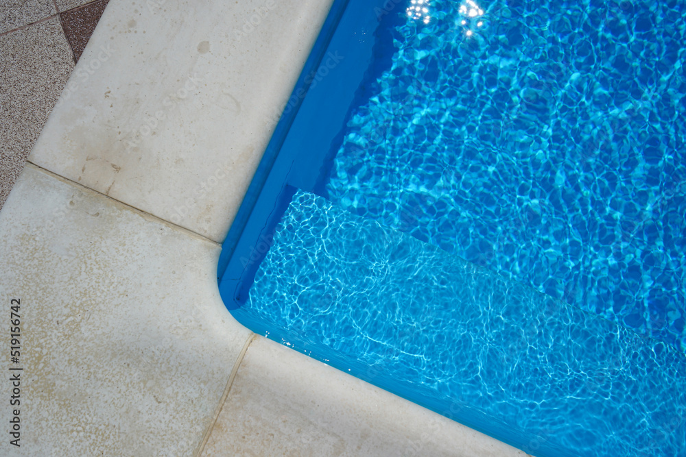 Obraz premium Swimming pool with blue water outdoors with stone gray edge, closeup. Top view.