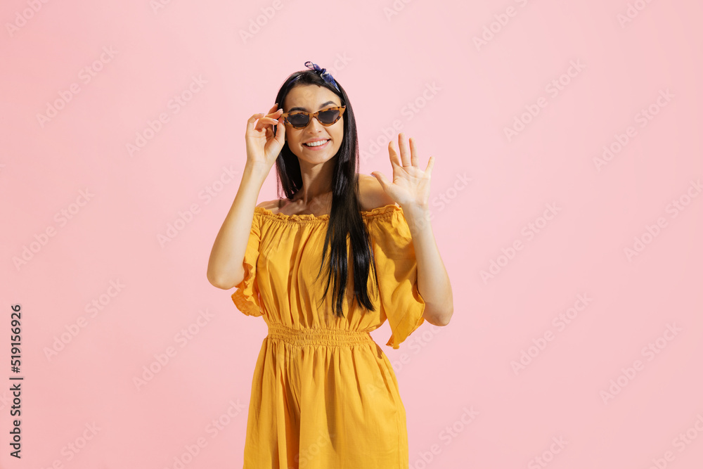 Portrait of young beautiful girl, student in summer yellow dress isolated on pink background. Concept of beauty, art, fashion, human emotions Portrait of young beautiful girl, student in summer yellow dress isolated on pink background. Concept of beauty, art, fashion, human emotions