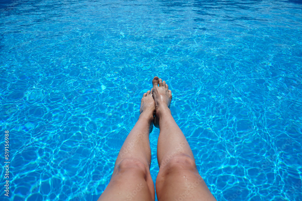 Legs of a beautiful young woman on the background of an outdoor pool.