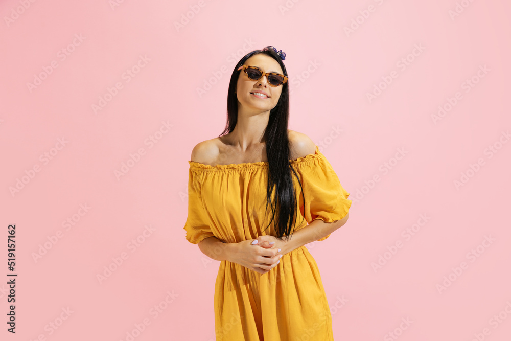 Portrait of young beautiful girl, student in summer yellow dress isolated on pink background. Concept of beauty, art, fashion, human emotions Portrait of young beautiful girl, student in summer yellow dress isolated on pink background. Concept of beauty, art, fashion, human emotions
