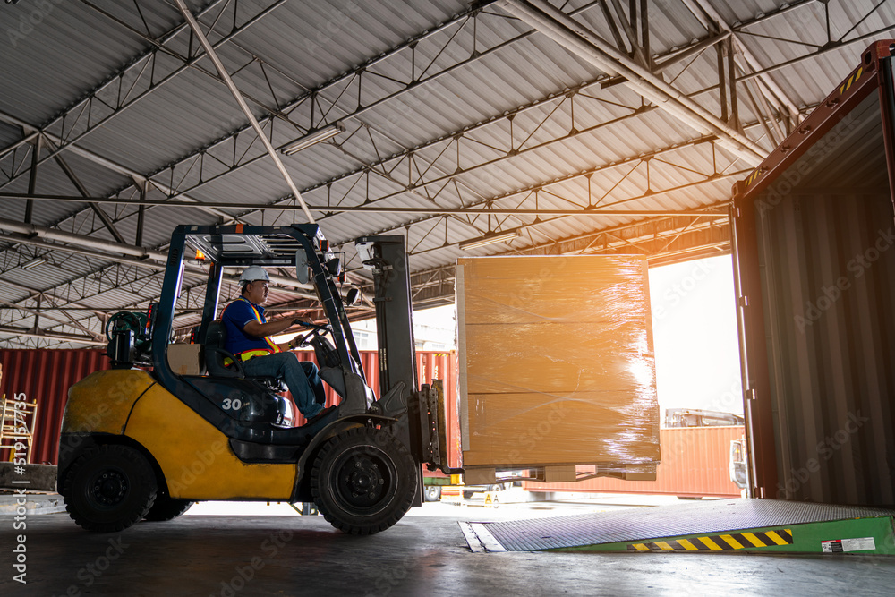 Warehouse worker driver in uniform delivery and loading pallet product by forklift.