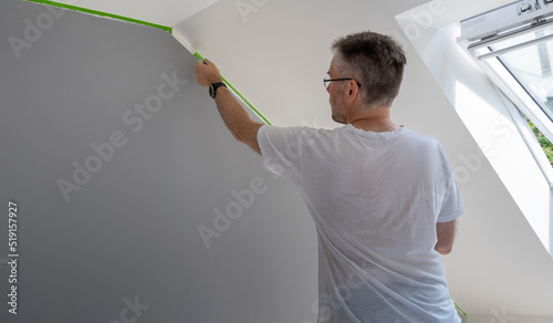 Photography Painter removes masking tape and creates a sharp border between a grey and white painted part of a wall