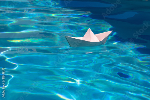Paper boat sailing on blue water surface. Paper boat on the sea background. Tourism, travel dreams vacation holiday. Cruise ship concept. Origami paper sailing boat.