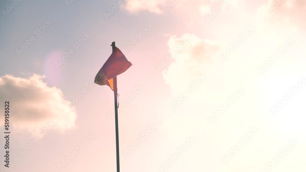 Red and yellow flag of Indonesia waves in wind against sun and sky on flagpole. National symbol of country. Red and yellow flag of Indonesia waves in wind against sun and sky on flagpole. National symbol of country.