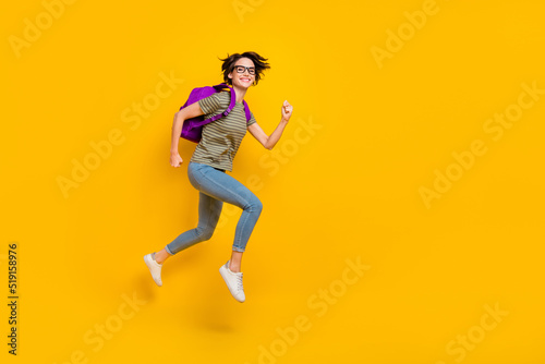 Full length photo of funny pretty girl dressed green t-shirt eyewear rucksack walking empty space isolated yellow color background