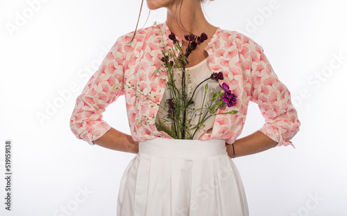 Flowers tucked into a woman’s skirt. Fragrant shower. Creative performance of flowers in clothes. Femininity. Women’s day