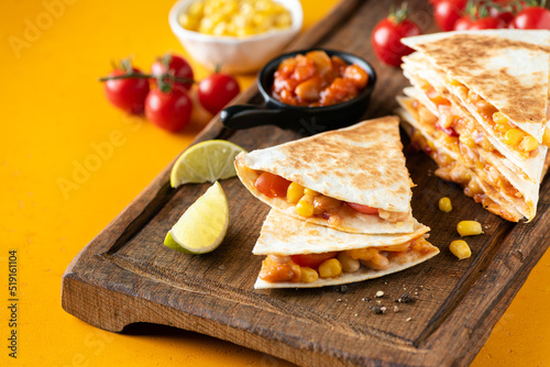 Delicious vegetarian quesadilla with tomato, baked beans and corn on yellow background, closeup view