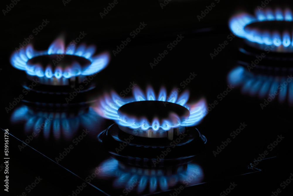 Flaming gas burners on household kitchen stove in the darkness Flaming gas burners on household kitchen stove in the darkness
