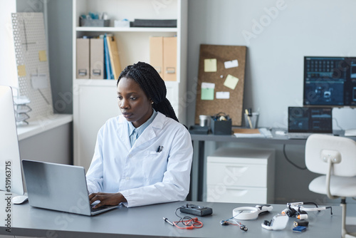 Portrait of young African American woman working in engineering lab and using laptop, copy space © Seventyfour