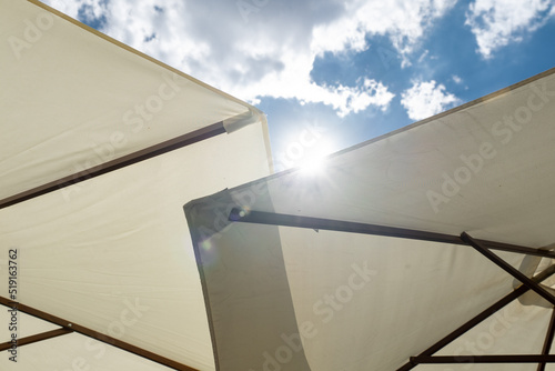 The sun glaring over the rim of a parasol making you feel there is no escape from the heat