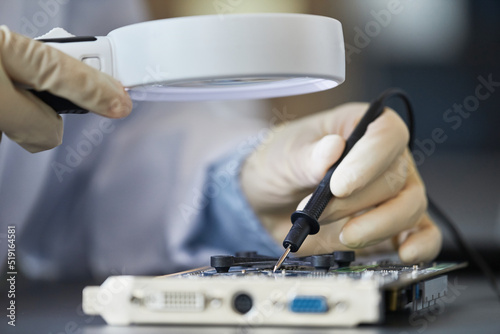Macro shot of female engineer inspecting hardware with magnifying glass, copy space