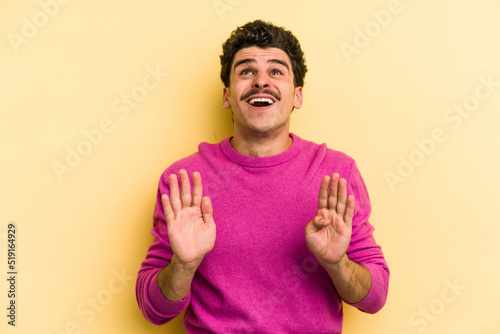 Young caucasian man isolated on yellow background screaming to the sky  looking up  frustrated.