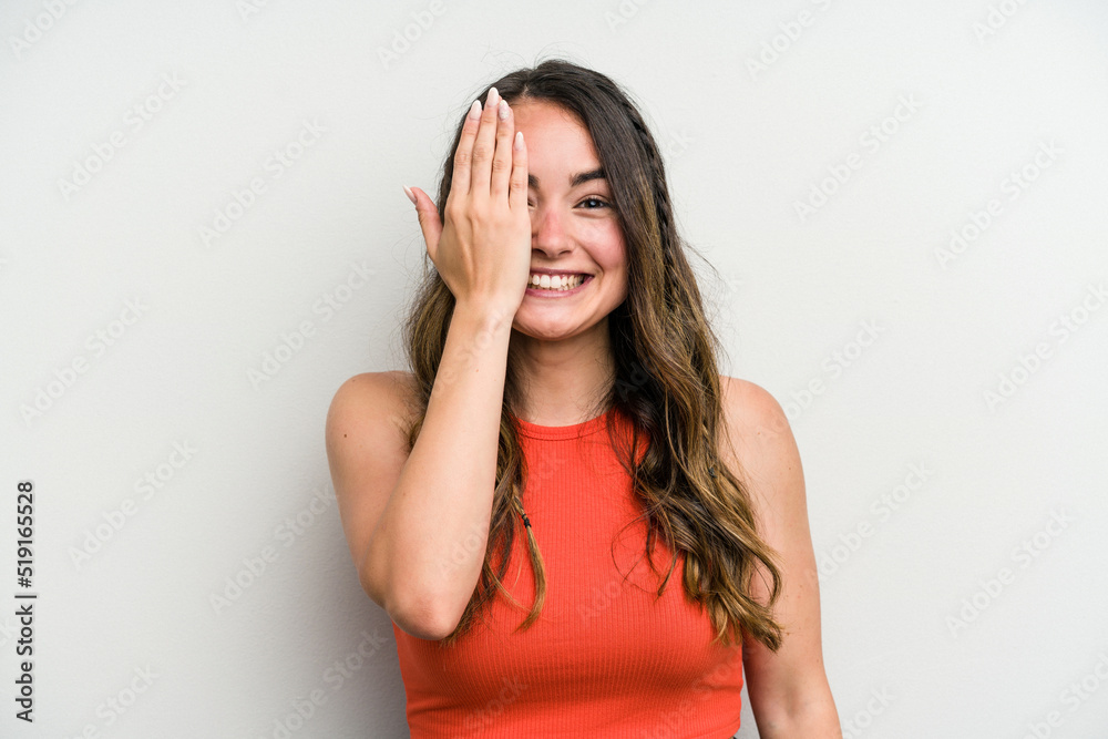 Young caucasian woman isolated on white background having fun covering half of face with palm.