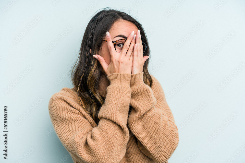 Young caucasian woman isolated on blue background blink through fingers frightened and nervous. Young caucasian woman isolated on blue background blink through fingers frightened and nervous.