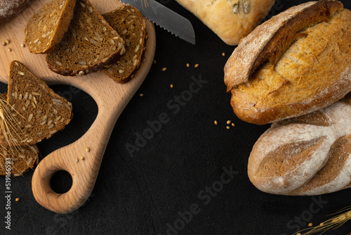 Varieties of gluten-free pastries on a wooden cutting board with a knife on a black background