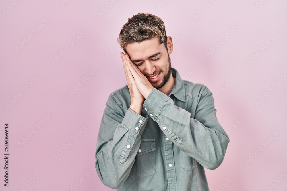 Hispanic man with beard standing over pink background sleeping tired dreaming and posing with hands together while smiling with closed eyes. Hispanic man with beard standing over pink background sleeping tired dreaming and posing with hands together while smiling with closed eyes.