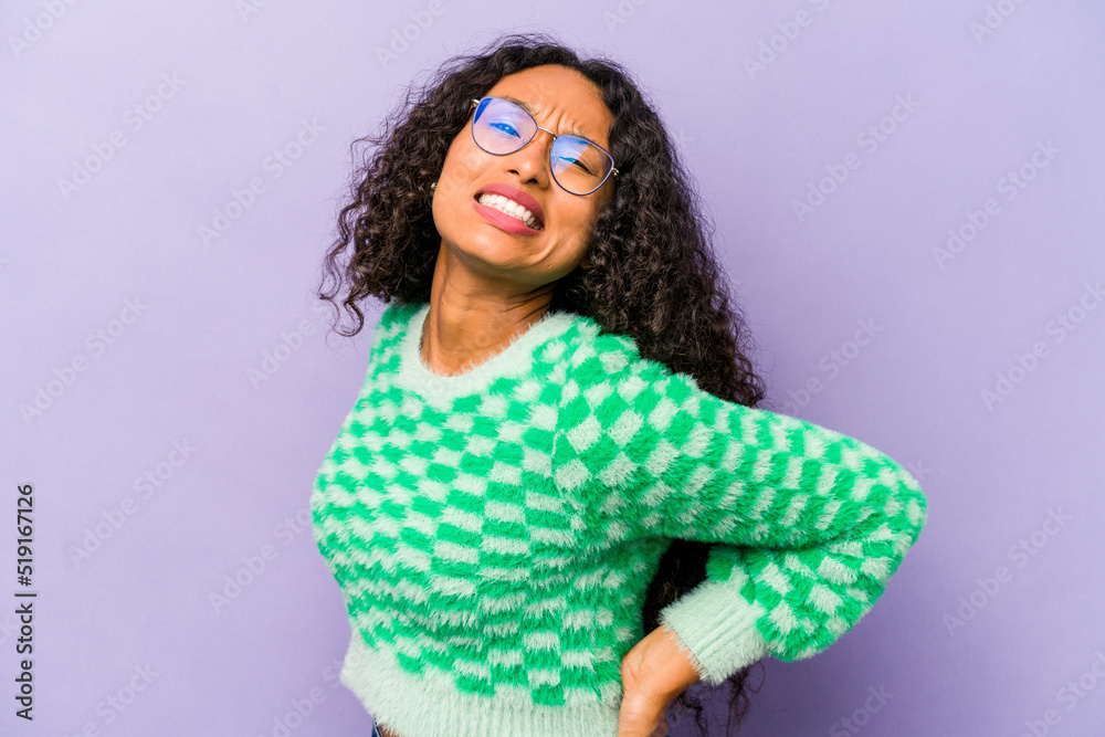 Young hispanic woman isolated on purple background suffering a back pain. Young hispanic woman isolated on purple background suffering a back pain.