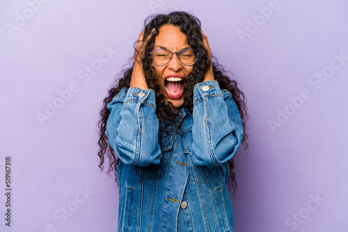 Young hispanic woman isolated on purple background covering ears with hands trying not to hear too loud sound. photo