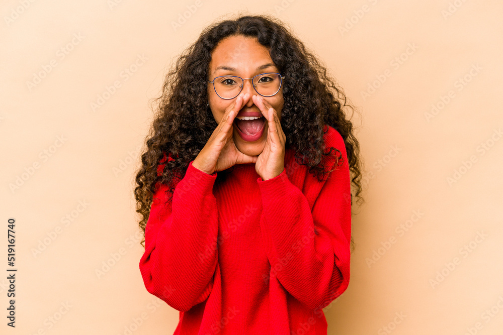 Young hispanic woman isolated on beige background saying a gossip, pointing to side reporting something. Young hispanic woman isolated on beige background saying a gossip, pointing to side reporting something.