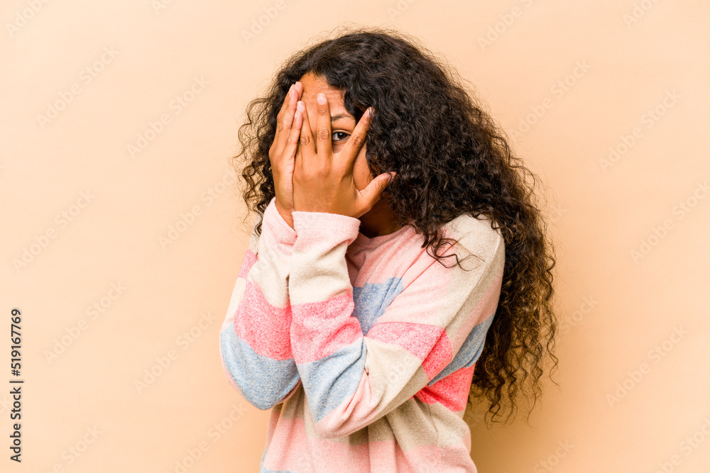 Young hispanic woman isolated on beige background blink through fingers frightened and nervous. Young hispanic woman isolated on beige background blink through fingers frightened and nervous.