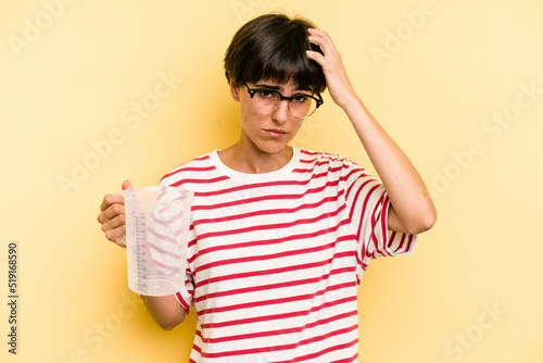 Young caucasian woman holding measuring jug isolated on yellow background being shocked, she has remembered important meeting.