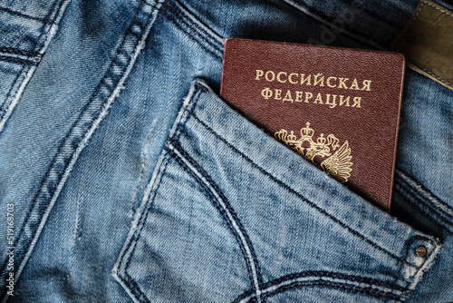 Passport of citizen of the Russian Federation peeking out from back pocket of old blue jeans close up