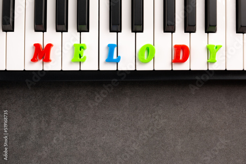 The word melody is composed of multicolored letters on the piano keys. Copy space. 