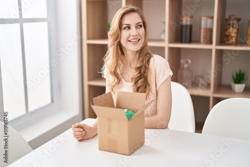 Beautiful blonde woman with cardboard box looking to side, relax profile pose with natural face and confident smile. © Krakenimages.com