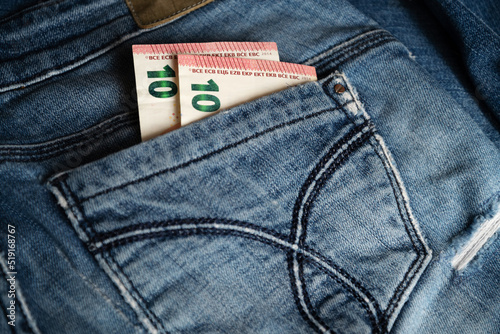 Two of ten euro banknotes peek out from back pocket of old blue jeans
