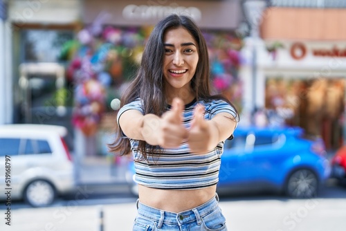 Young hispanic girl smiling confident pointing with fingers at street