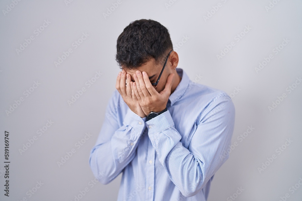 Handsome hispanic man wearing business clothes and glasses with sad expression covering face with hands while crying. depression concept. Handsome hispanic man wearing business clothes and glasses with sad expression covering face with hands while crying. depression concept.