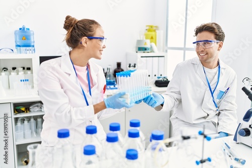 Man and woman wearing scientist uniform holding test tube at laboratory
