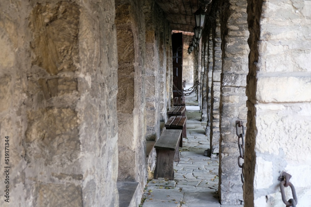 Stone cloisters wich metal chaines and standing wooden benches Stone cloisters wich metal chaines and standing wooden benches