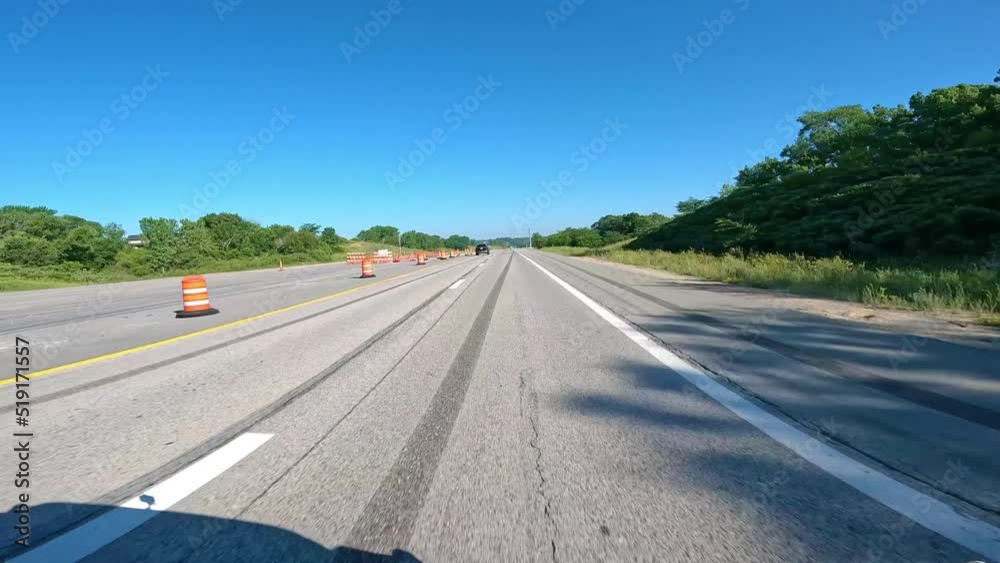 POV while driving on The Avenue of the Saints highway in rural Iowa; driving through an area where traffic is diverted with construction barrels; driving past fields and agricultural landscapes POV while driving on The Avenue of the Saints highway in rural Iowa; driving through an area where traffic is diverted with construction barrels; driving past fields and agricultural landscapes