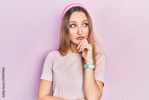 Young blonde girl wearing casual clothes with hand on chin thinking about question, pensive expression. smiling and thoughtful face. doubt concept.
