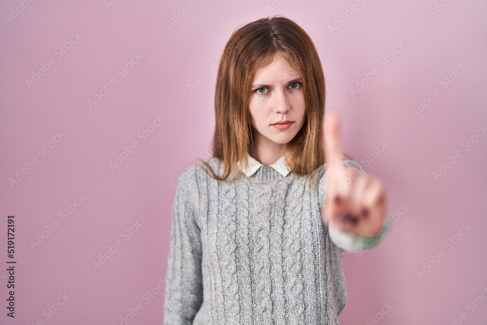 Beautiful woman standing over pink background pointing with finger up and angry expression, showing no gesture Beautiful woman standing over pink background pointing with finger up and angry expression, showing no gesture