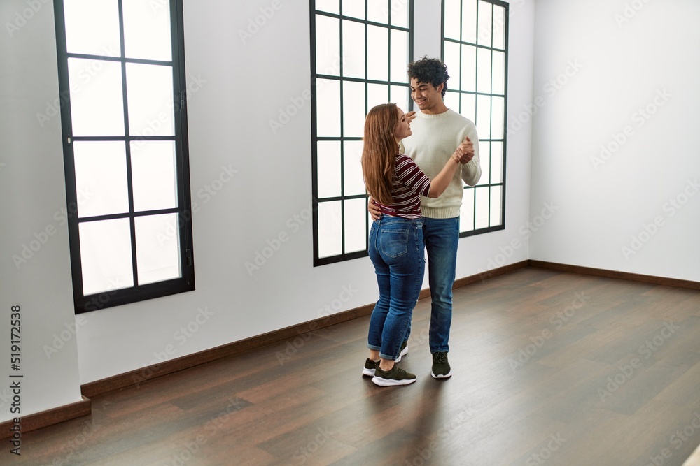 Young hispanic couple smiling happy dancing at empty new home. Young hispanic couple smiling happy dancing at empty new home.