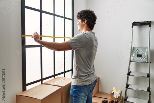 Young hispanic man smiling happy moving at new home.