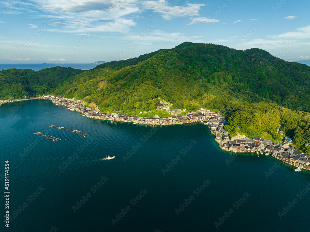Aerial view of small boat approaching coastal fishing village by mountain